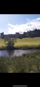 a river in a field with a city in the background at Amble Holiday Home in Amble