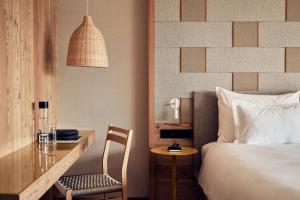 Cette chambre comprend un lit, un bureau, une table et une chaise. dans l'établissement Falkensteiner Hotel Kronplatz - The Leading Hotels of the World, à Brunico