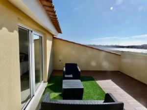 a balcony with two chairs and green grass at Villa Barrinha in Praia de Mira