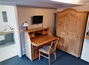 Zimmer mit einem Schreibtisch, einem TV und einem Stuhl in der Unterkunft Hotel Restaurant Landluft in Aerzen