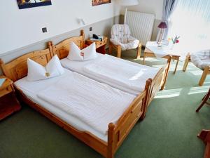 a bedroom with a large wooden bed with white sheets at Hotel Restaurant Landluft in Aerzen