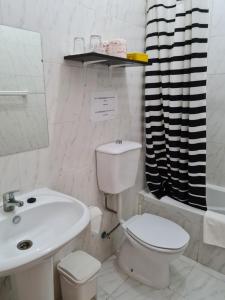 a white bathroom with a toilet and a sink at Djarfogo house in S&atilde;o Filipe