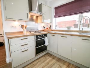 een keuken met witte kasten en een fornuis met oven bij Hollinwell View in Nottingham