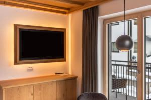 a living room with a television and a balcony at La Grambla App Sella 1 in Santa Cristina in Val Gardena