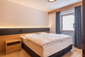 - une chambre avec un grand lit et une fenêtre dans l'établissement La Grambla App Sella 1, à Santa Cristina Valgardena