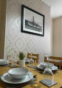 a table with plates and glasses and a bridge on the wall at 4-5 Bedroom House For Corporate Stays in Kettering in Kettering