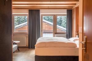 a bedroom with a bed and a large window at La Grambla App Saslonch in Santa Cristina Gherdëina
