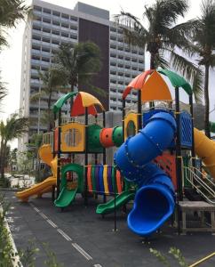 a playground in front of a building with palm trees at Salinas Premium Resort in Salinópolis