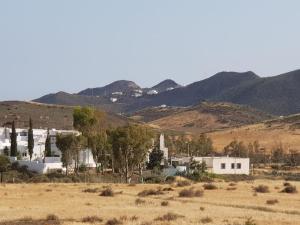 a white building in a field with mountains in the background at Las Cuatro Lunas in Níjar