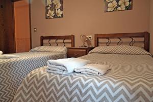 2 camas con toallas en una habitación en Hotel rural val dos pigarros, en Lubián