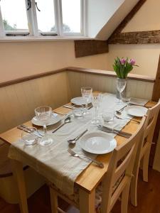 a wooden table with plates and glasses on it at Stunning 2 Bedroom Flat in a Central Location in New Alresford