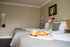 a bed with a plate of bread and a glass of orange juice at The Harbour Inn in Buncrana