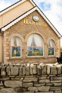 een gebouw met een klok bovenop een stenen muur bij The Harbour Inn in Buncrana