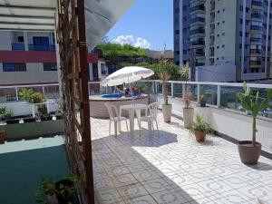 a patio with a table and umbrella on a balcony at Cobertura Maravilhosa com área livre in Vitória