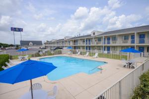 una piscina con sillas y sombrillas frente a un hotel en Motel 6-Webster, TX - Houston - Nasa Lake, en Webster