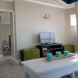 a living room with a table and two green chairs at Cascades Self-Catering Apartments in Summerstrand