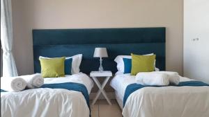 a bedroom with two beds with green and white pillows at Cascades Self-Catering Apartments in Summerstrand