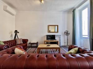 ein Wohnzimmer mit einem Ledersofa und einem Tisch in der Unterkunft Congrès Carré d'Or by Booking Guys in Nizza