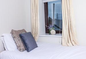 1 cama con almohada y ventana en Bright 3bed sleeps 9 with secret garden 5min walk to town, en Sligo