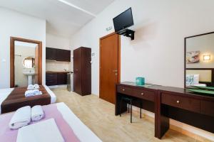 a room with a bed and a desk with a television at Villa Yanna in Olympiada