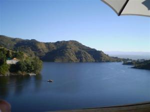 a view of a lake with a house on a mountain at Complejo Cabañas Foxes Frente al Lago in Villa del Dique