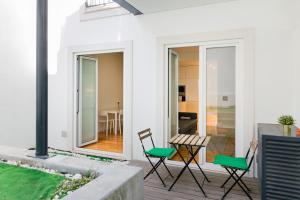 Casa blanca con sillas verdes y patio en Senhora do Monte Apartment 1(dto) with Outdoor Area, en Lisboa