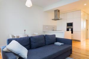 uma sala de estar com um sofá azul e uma cozinha em Senhora do Monte Apartment 2(esq) with Outdoor Space em Lisboa