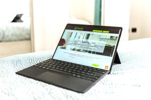 laptopa siedzącego na łóżku w obiekcie Hostly - The Urban Garden House - 3 Bedrooms, Garden, Great Location! w Pizie
