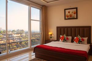 a bedroom with a bed and a large window at SERENE SUITES in Dharamshala