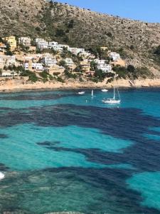 a boat floating in the water near a beach at One Bed Apartment overlooking Jalon Valley, Costa Blanca in Alcalalí