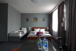 Un dormitorio con una cama y una mesa con botellas. en Hotel Evita Tashkent en Tashkent