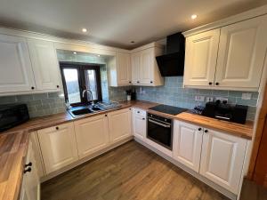 una cocina con armarios blancos y fregadero en 3 Bed Detached Cottage- Log Burner Mountain Views, en Beaumaris
