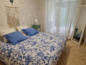 Schlafzimmer mit einem blauen und weißen Bett und einem Fenster in der Unterkunft Le jardin de Bonporteau in Cavalaire-sur-Mer