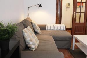 un sofá con almohadas en la sala de estar en Bilbao Apartment Lasai con parking directo, en Bilbao