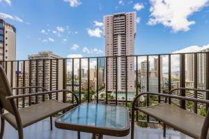 a balcony with chairs and a table and a view of buildings at Ohia Waikiki Studio Suites in Honolulu
