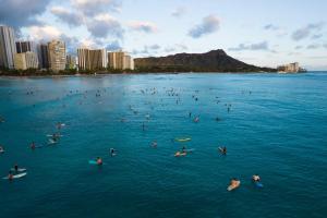 a large group of people swimming in the ocean at Ohia Waikiki Studio Suites in Honolulu