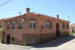 ein rotes Backsteingebäude mit Fenstern auf einer Straße in der Unterkunft VUT Flor de Romero in Los Yébenes