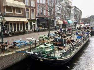 un barco está atracado en un canal con mesas y sillas en Best Location in Centrum en Leiden