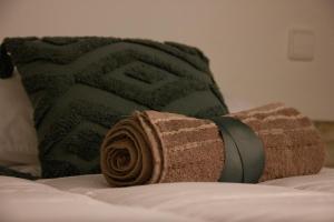 una toalla enrollada en una cama junto a una almohada en El museo, en Ávila