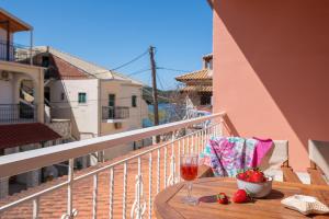 a table with a glass of wine and strawberries on a balcony at Τrilogy Studios in Syvota