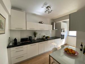 a kitchen with white cabinets and a bowl of fruit on a table at Cosy Avenida Apartment in Faro