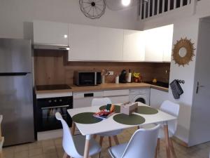 a kitchen with a white table and white chairs at Mazet 55 Gorges du Verdon in Saint-Martin-de-Brômes