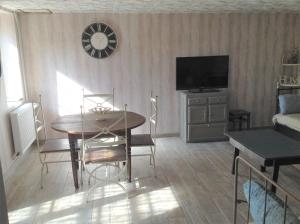 a living room with a dining table and a television at L'Ancien Pressoir in Pierrefitte-en-Cinglais