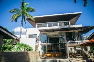 a house with a palm tree in front of it at Mother Earth Luxury Boutique Hotel, Restaurant & Spa in Tamarindo