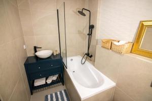 a bathroom with a sink and a shower and a tub at SAND Apartment in Žilina