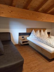 un letto con cuscini bianchi e un divano in camera di Hotel Alpenfrieden a Kappl