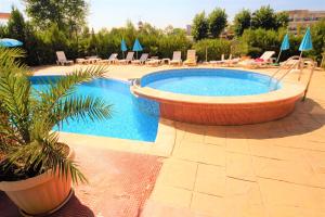 una piscina en un complejo con sillas y una palmera en Menada Apartments in Sunny Beach, en Sunny Beach