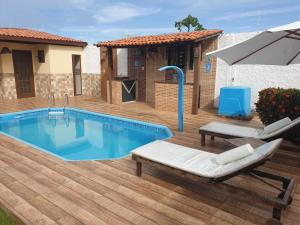 a swimming pool with two lounge chairs and an umbrella at Porto Feliz in Barra de Jacuípe