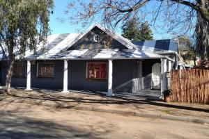 a blue house with a fence in front of it at Karoo Refresh Cheerful 2 Bedroom House in Oudtshoorn