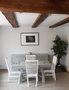 a white dining room table with white chairs and a plant at Les Colombages in Colmar